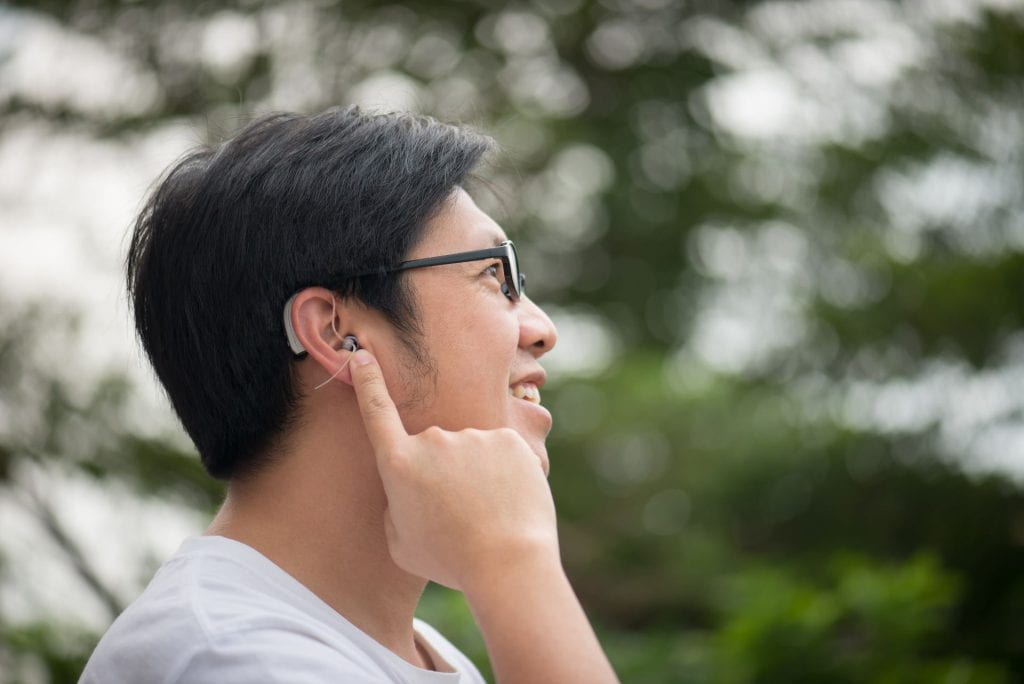 Person pointing towards hearing aid